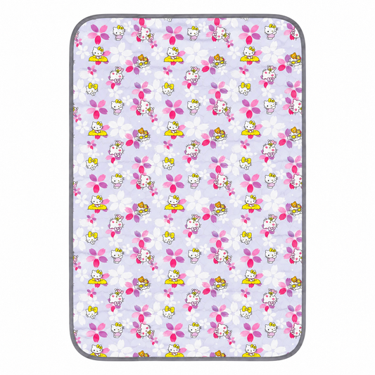 A rectangular mat with rounded corners featuring a repeating Hello Kitty pattern on a light lavender background. The pattern includes pink flowers, white blossoms, and Hello Kitty characters in yellow, pink, and white.