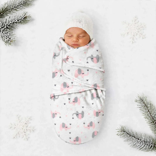 A sleeping newborn baby swaddled in a soft white blanket with a pink and gray elephant print, wearing a white knit hat, laid on a white background with decorative pine branches and snowflakes.