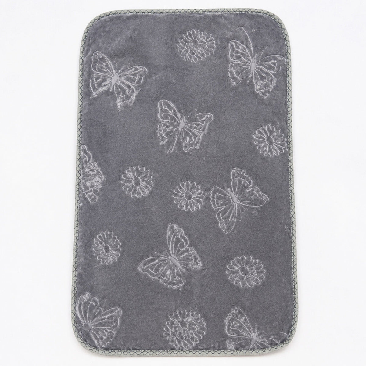 A dark gray rectangular mat with rounded corners, featuring a light gray embroidered pattern of butterflies, dandelions, and flowers, finished with a gray braided border, shown on a white background.