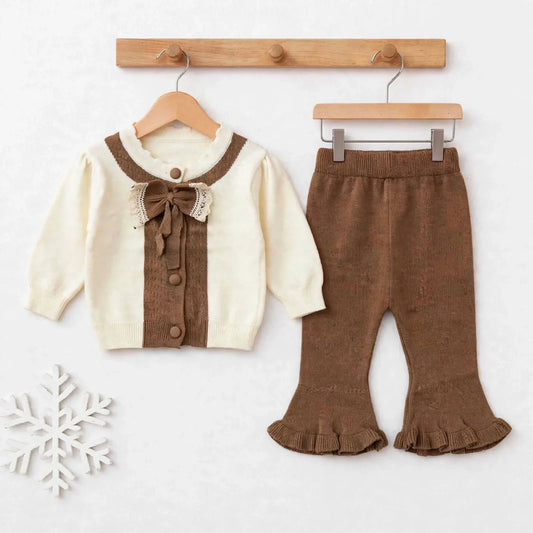 A toddler girl's two-piece knit outfit set featuring a cream cardigan with brown trim and a matching brown ruffled flared pant, displayed on wooden hangers against a light background.