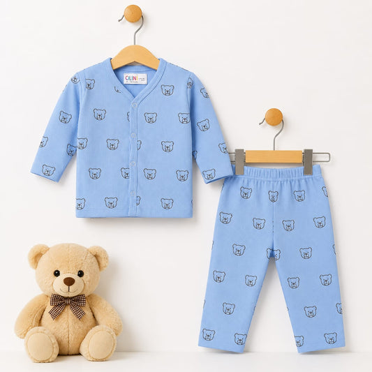 A baby two-piece outfit set consisting of a light blue long-sleeve button-front cardigan and matching pants, both printed with a small bear face pattern. The set is displayed on wooden hangers against a white background, with a plush teddy bear wearing a 