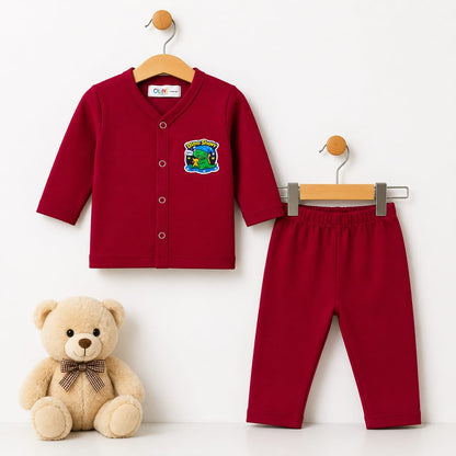 A two-piece baby outfit set consisting of a long-sleeve red cardigan and matching red pants, displayed on wooden hangers next to a beige teddy bear. The cardigan features a colorful dinosaur patch on the left chest.