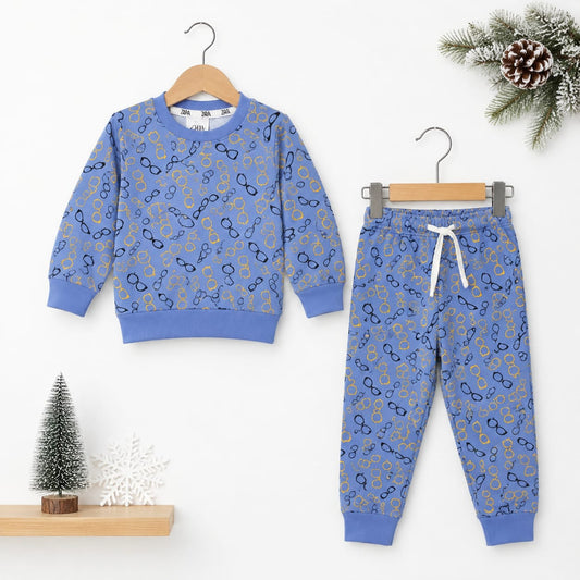 A children's two-piece sweatshirt and jogger pants set in a dusty blue color, decorated with a repeating pattern of gold and navy glasses. The sweatshirt is shown on a wooden hanger on the left, and the matching pants are shown on a metal hanger on the ri
